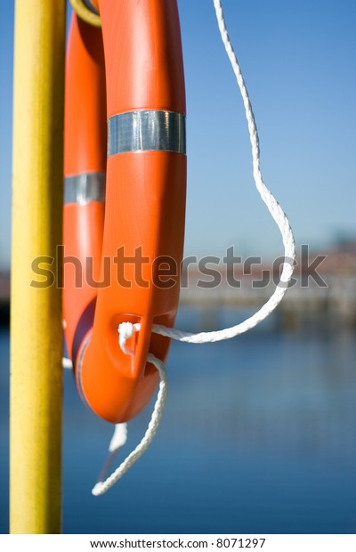 Orange life buoy hanging\
near the river