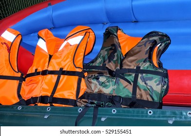 Orange life jackets and life jacket of camouflage color lie on the red-blue inflatable boat