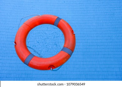 Orange Life Ring With Blue Water In The Pool Which It Is Equipment For Help Someone Can Not Swimming And Drowning.