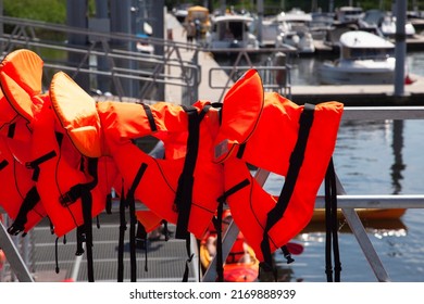 Orange Life Vests On Sail Deck In The Harbor Port Bay. Rescue Equipment, Life Jacket, Summer Concept.