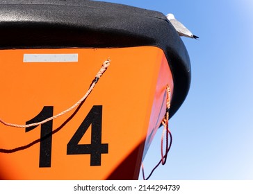 Orange Lifeboat On Side Of North Sea Ferry Boat Crossing Channel To France Or Holland For Passengers To Escape Sinking Ship. Emergency Life Preserve With Number 12 On The Side In Black Font.