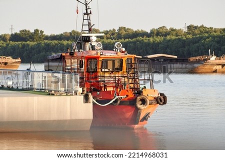 Orange lifeboat (rescue) ship near the pier in the river port