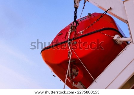 an orange lifeboat still hanging