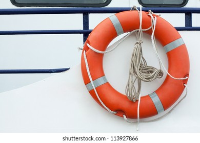 Orange lifebuoy and old rope hanging on a boat - Powered by Shutterstock