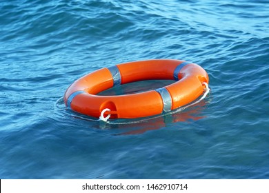 Orange Lifebuoy In Sea On Water. Life Ring Floating On Top Of Water. Life Ring In Ocean.