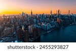 Orange light of setting sun illuminating the skyscrapers and high-rise buildings in New York scenery. Top view on the metropolis from above the East River.