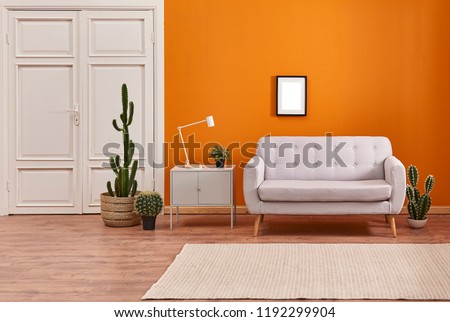 Orange living room and orange wall background light grey sofa and avangard white door. Modern home decoration brown parquet and carpet design.