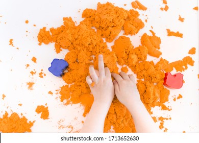 Orange Magic Sand In A Kids Hands On A White Background Close Up. Early Sensory Education. Preparing For School. Development