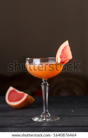 Orange margarita alcohol cocktail with grapefruit on black table side view
