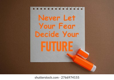 Orange marker and a note written never let your fear decide your future, self-development concept, motivation to change life for the better, plan the future without fear, dare to act