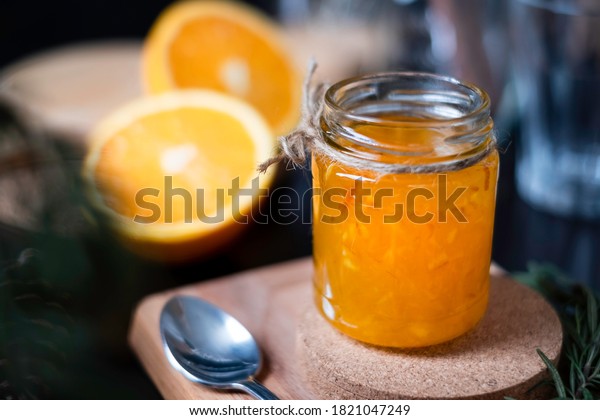 Orange marmalade / orange jam in glass jar. A confiture\
is any fruit jam, marmalade, paste or fruit stewed in thick syrup.\
Orange marmalade & fruit jam in glass jar concept. Dark food\
photography. 