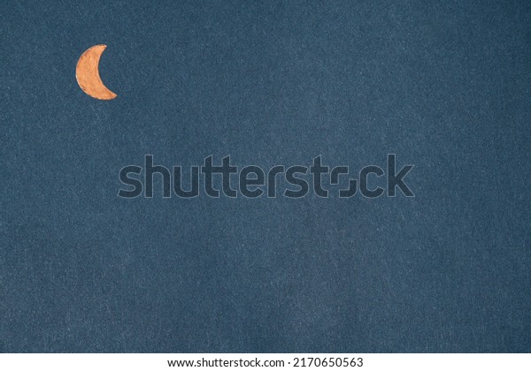 Orange metal crescent moon on navy\
blue kraft paper. Textured background with geometric\
shapes
