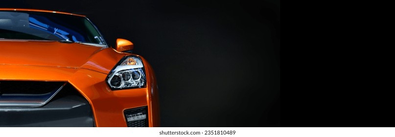 Orange modern car headlights on black background, copy space, banner side	