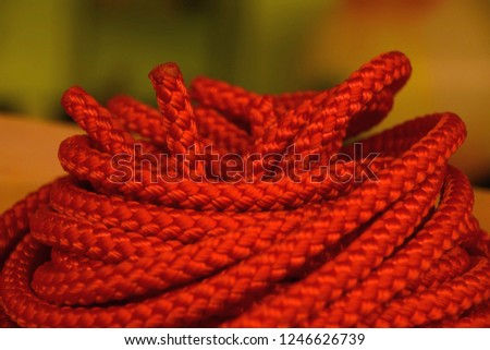 orange nylon rope roll in front of blurred background, coiled orange industrial rope made of nylon or synthetic