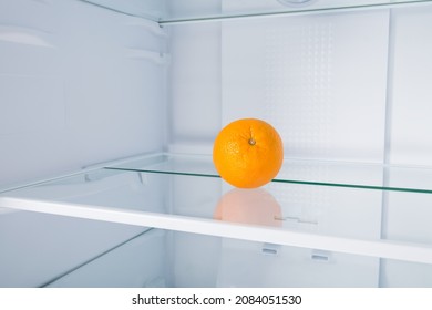 An Orange On A Shelf In An Empty Fridge