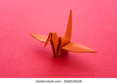 Orange Origami Paper Crane On Red Background.