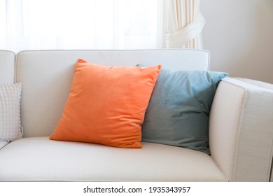 Orange and pale green pillows on the sofa.