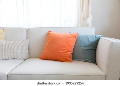 Orange and pale green pillows on the sofa.