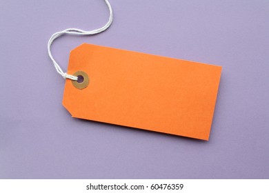 Orange Paper Luggage Tag With Copy Space On A Purple Background