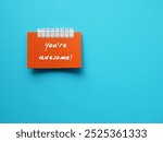 Orange paper note on copy space blue background with text written YOU