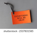 Orange paper tag with text written Everything Will Be Okay - phrase of comfort in times of stress or uncertainty - faith that the balance of life will be restored