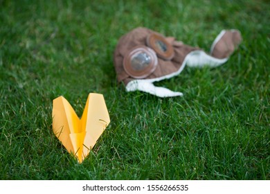 orange paper toy plane and pilot's helmet on fresh green grass, selective focus  - Shutterstock ID 1556266535