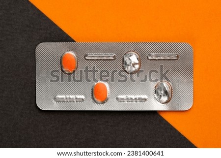 orange pill on black baground and Used blister pack on orange background
