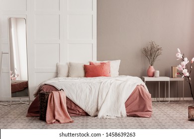 almohadas naranjas en cama king size blanca en una habitación femenina de moda