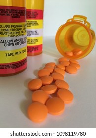 Orange Pills Spill Out Of A Bottle. Other Pill Bottles Show Their Warning Labels.