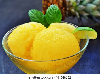 Orange pineapple sorbet scoops with lime in glass bowl