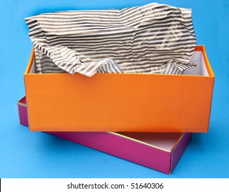 Orange And Pink Fancy Gift Box Opened With Striped Tissue Paper On A Blue Background.