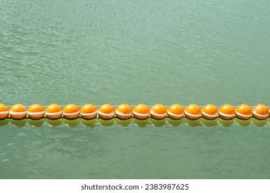 An orange plastic buoy floats on the surface of the water. To indicate the boundaries of no-hunting areas, protected areas, and dangerous areas. Do not enter. - Powered by Shutterstock
