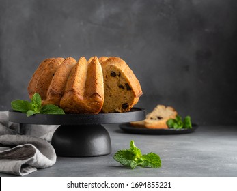 Orange Pound Cake With Dried Cherry Decorated With Fresh Mint Leaves On Black Wooden Plate. Grey Concrete Background. Copy Space. Homemade Easy Cooking Dessert.