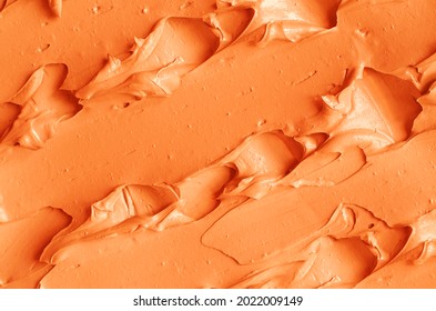 Orange pumpkin mask (facial cream, turmeric body scrub, terracotta clay) texture close up, selective focus. Abstract background with brush strokes. 