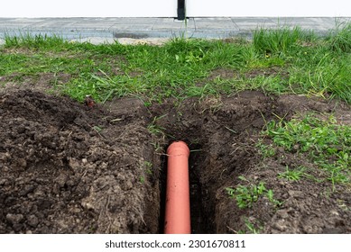 Orange PVC pipe buried in the ground connected to the gutter, used to connect to the drainage pipe.