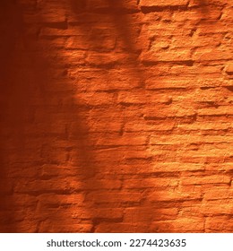 Orange red brown brick wall of the house. Close-up. Light and shadow from the leaves of trees. Bright vintage background for design. Burnt orange color shade. Rough surface texture. Painted plaster., fotografie de stoc