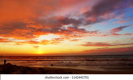 Orange and red sunset at Mancora sandy beach with cloudy and blue sky,  north Peru, Pacific ocean