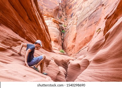 Orange red wave sandstone abstract formations and man climbing rocks at narrow Antelope slot canyon in Arizona on trail from Lake Powell