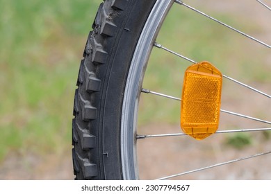 Orange reflector on the bicycle wheel. Safety device. Bike wheel reflector.