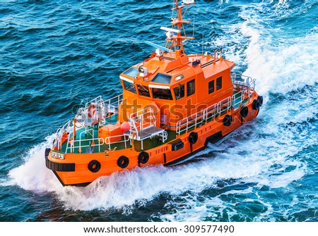 Orange rescue or coast guard patrol boat industrial vessel in blue sea ocean water