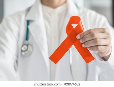 Orange Ribbon For Awareness On Leukemia, Kidney Cancer, RDS Disease, Multiple Sclerosis, ADHD Illness, Chronic Obstructive Pulmonary Disease (COPD) In Doctor's Hand (bow Isolated With Clipping Path)