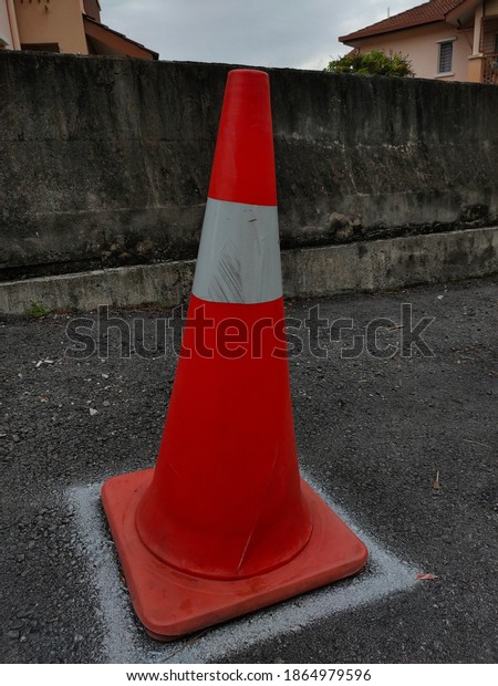Orange road\
cone with white stripes on the\
street.