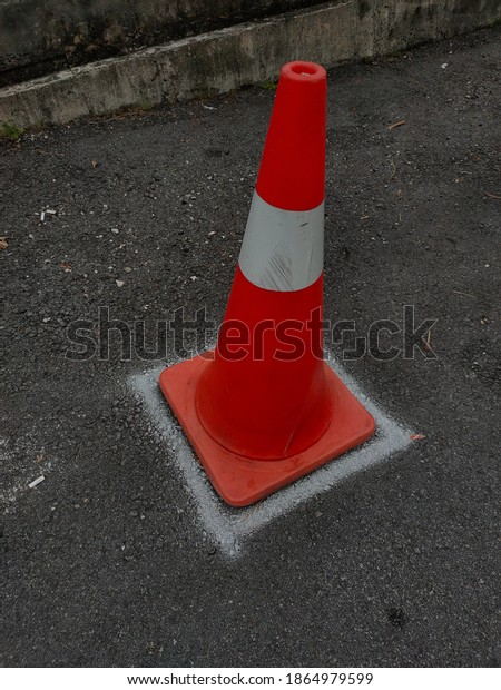 Orange road\
cone with white stripes on the\
street.