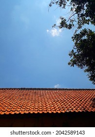 Orange Roof Tiles And Blue Sky, In Stark Contrast With Tree Branches