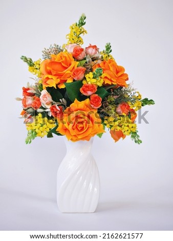 Orange roses artificial flowers bouquet in vase isolated on white  background or wallpaper ,mother's day ,still life ,women's day festive background ,colorful elegant ,congratulations card ,decorative