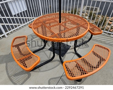 Orange round metal outdoor dining table with attached bench seats