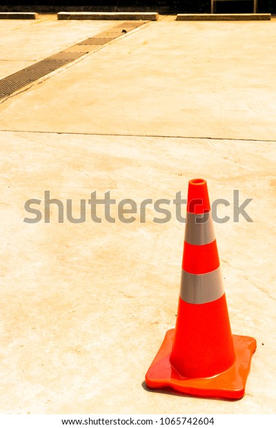 Orange rubber cone on the concrete road,  Orange\
and gray cone,