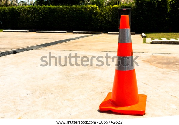 Orange rubber cone on the concrete road,  Orange\
and gray cone,