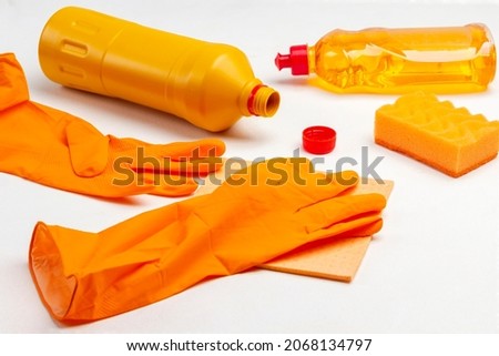 Orange rubber gloves, orange rag and orange plastic bottle. White background. Top view