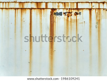 Orange rust streaks down a white wall